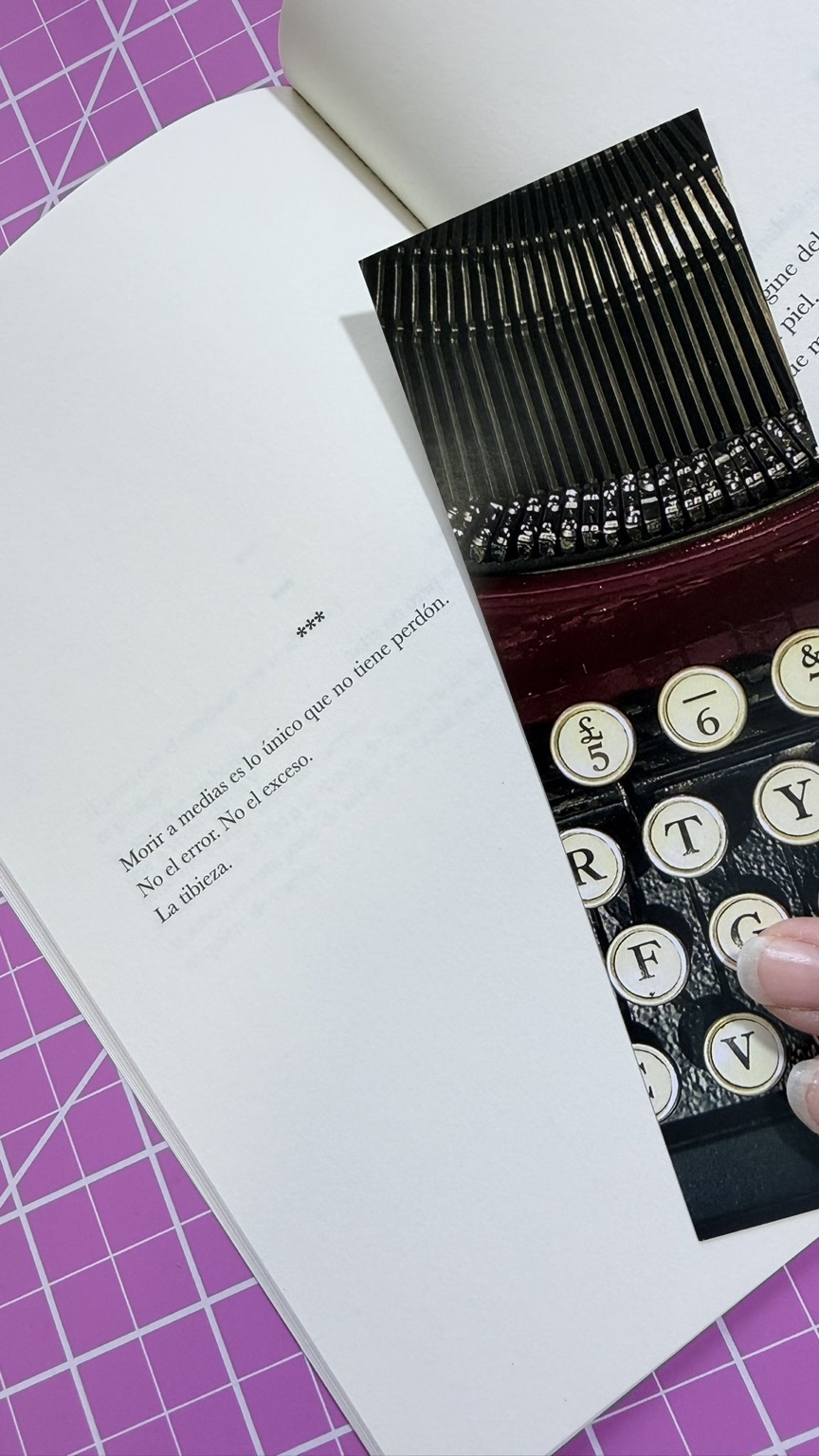 Página del libro junto a una máquina de escribir. Se lee: Morir a medias es lo único que no tiene perdón. No el error. No el exceso. La tibieza.
